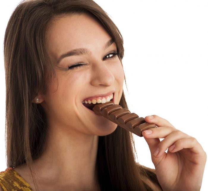Beautiful young caucasian woman eating chocolate